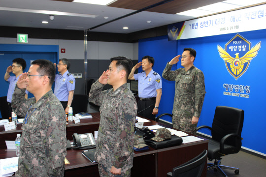 해경과 해군 관계자들이 정부세종2청사에서 협조회의를 진행하기 전 태극기를 향해 거수경례를 하고 있다. 해양경찰청 제공